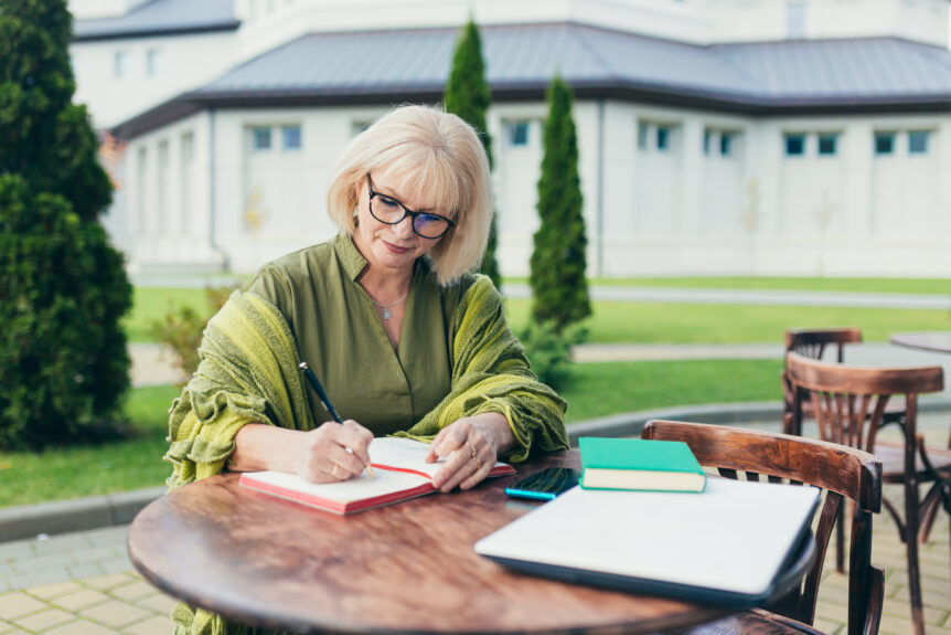 A retired female executive reviewing her financial plans on a sunny patio, symbolizing the security of predictable retirement income strategies.