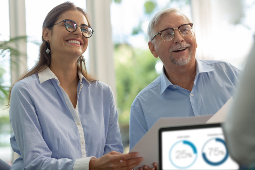 A smiling young woman and an elderly man in a positive meeting about retirement planning alternatives. They appear enthusiastic, holding documents while discussing flexible and secure retirement strategies beyond the traditional 401(k).